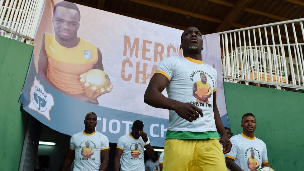 Guinea"s National football team players enter the stadium under a poster of late football player Cheick Tiote at the stade de la paix in Bouake on June 10, 2017 during 2019 African Cup of Nations qualifyer football match between Ivory Coast and Guinea.