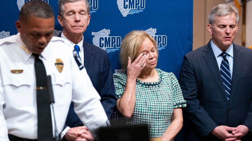 Charlotte Mayor Vi Lyle, second from right, flanked by North Carolina Governor Roy Cooper, second from left, and state Attorney General Josh Stein, right, wipes her eye as Charlotte Police Chief Johnny Jennings speaks to reporters April 30, 2024 in Charlotte, North Carolina.