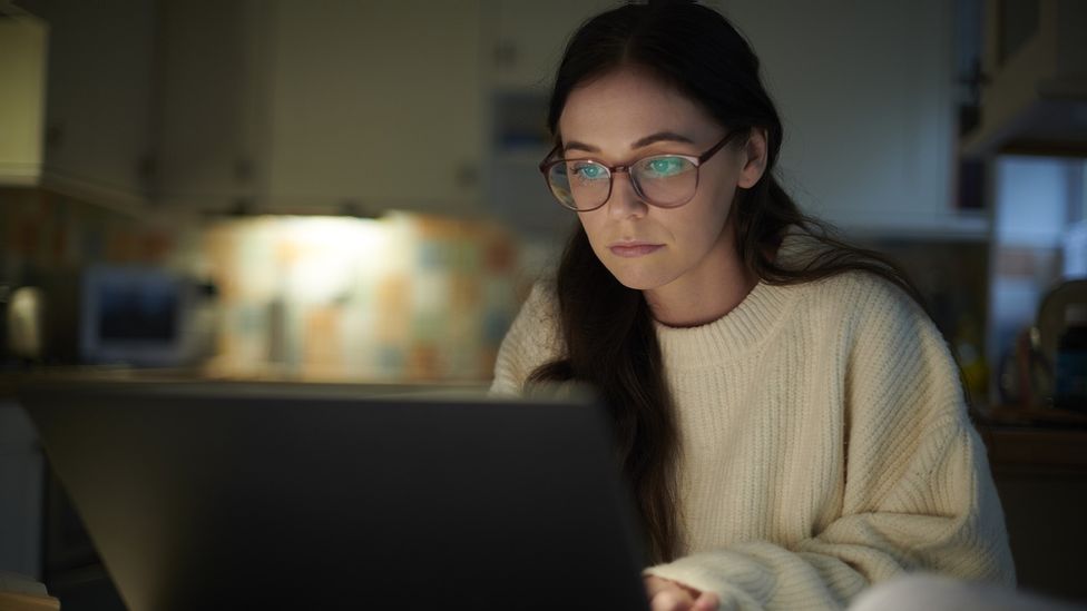 A teen   looking astatine  her laptop astatine  n night