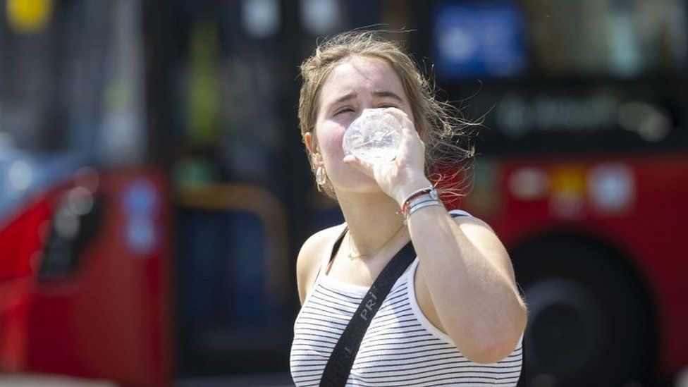 Woman drinking water during hottest days in summer 2022