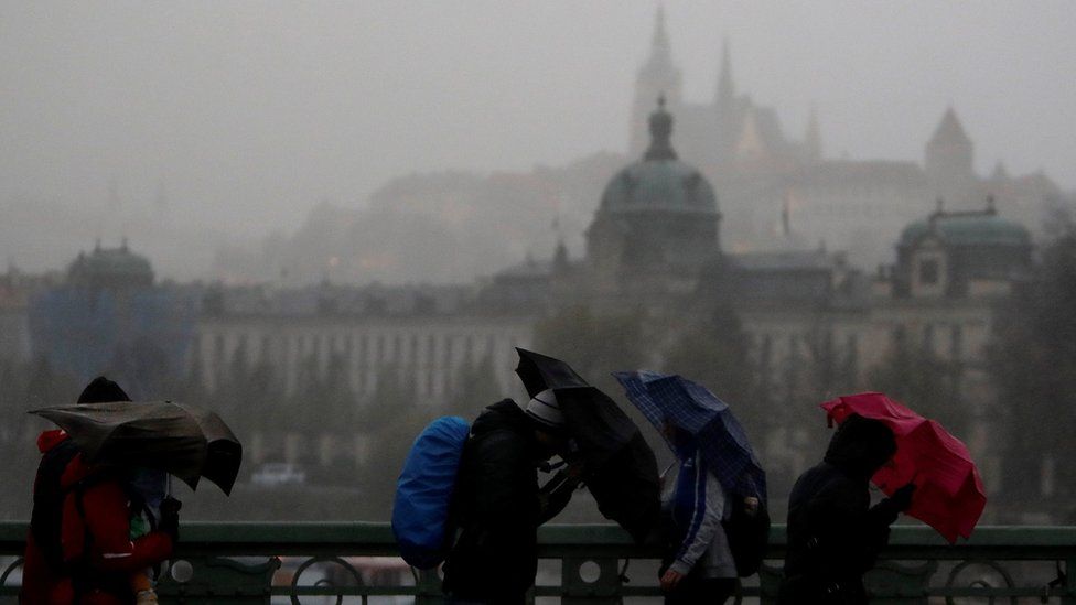 People hold umbrellas in heavy rain and strong wind in Prague