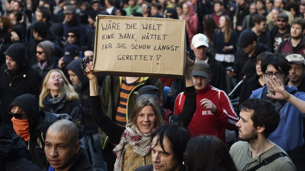 A protestor holds up a placard which reads 'If the world were a bank, you would have saved it already' during a rally on the opening day of the European Central Bank (ECB) in Frankfurt am Main, western Germany