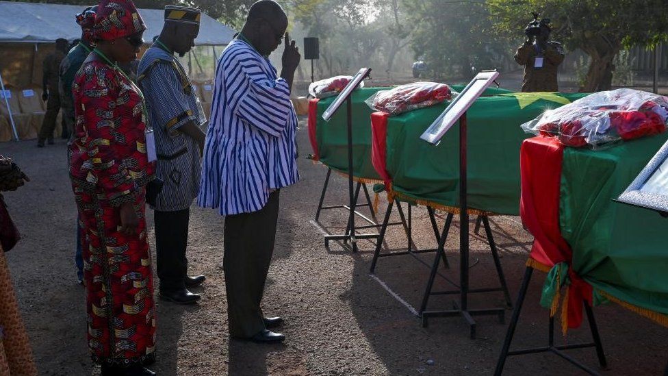 A relative of the former leader and revolutionary Thomas Sankara’s companion pays respects while standing by flag-draped coffins of Sankara and his companions before the burial of their remains in Ouagadougou, Burkina Faso February 23, 2023