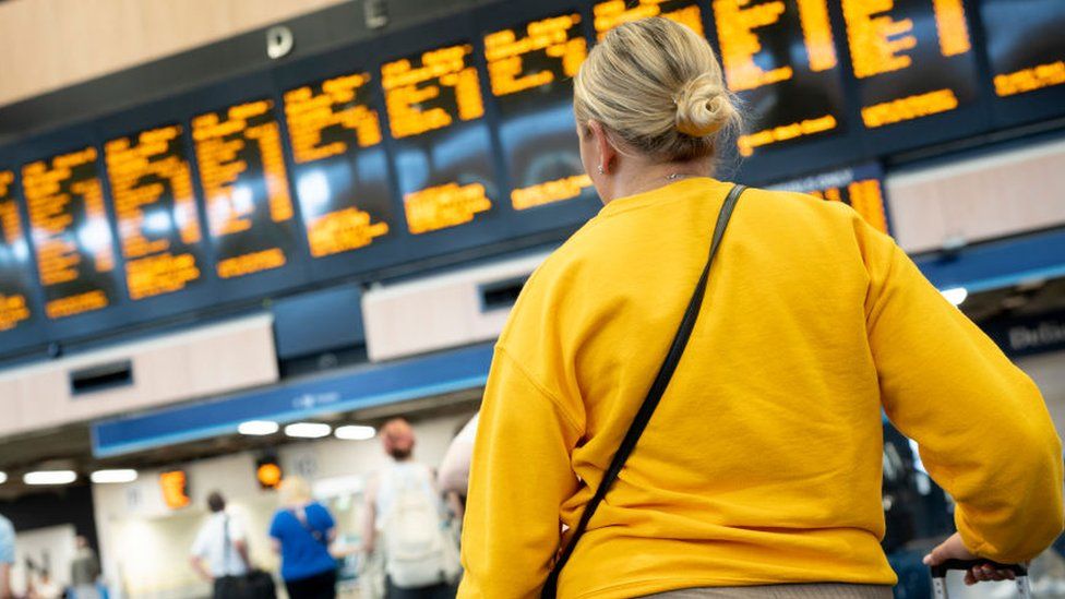 Woman looks at rail departures board
