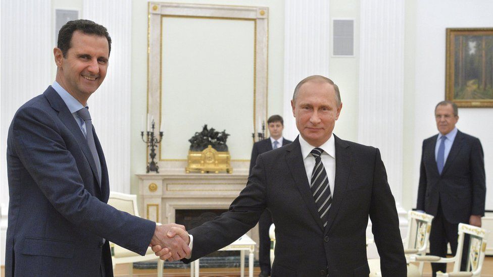 Russian President Vladimir Putin (R) shakes hands with Syrian President Bashar al-Assad