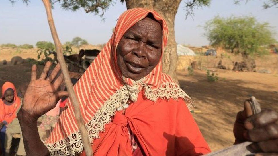 Дейфа Адам Юссуф, суданская беженка, бежавшая от насилия в суданском регионе Дарфур, реагирует, стоя в своем импровизированном убежище под деревом, недалеко от границы между Суданом и Чадом в Куфруне, Чад, 9 мая 2022 г.