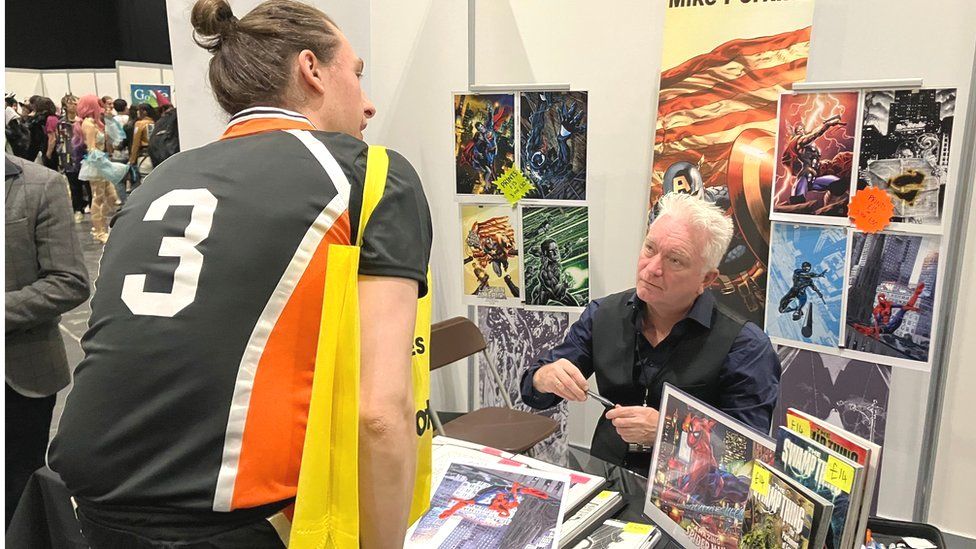 Mike Perkins autographs a Spider-Man poster for a fan