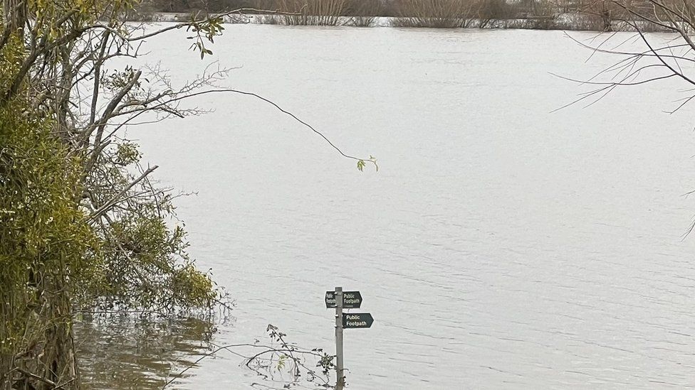 Flood water with a public footpath sign sticking out of the water