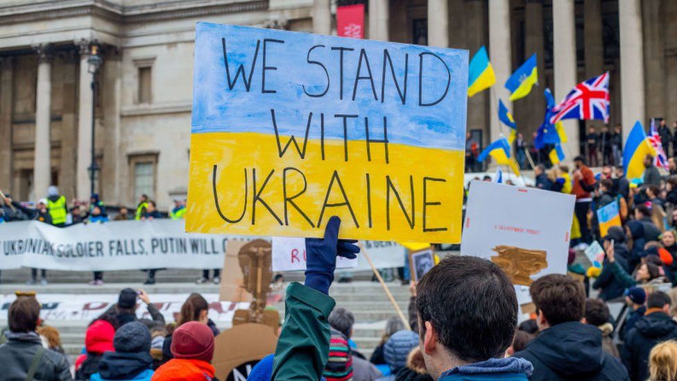 A protester holds a sign saying "We Stand With Ukraine" during a protest against Russia's invasion of Ukraine in London