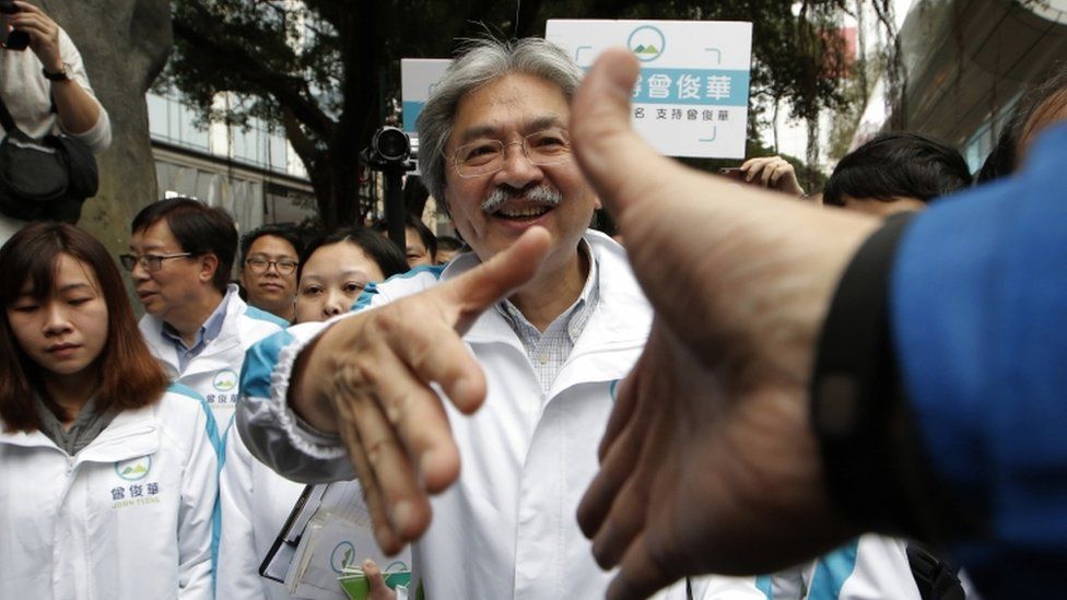 In this Saturday, 18 March 2017 photo, Hong Kong chief executive candidate former Financial Secretary John Tsang shakes hands with supporters during an election campaign in Hong Kong