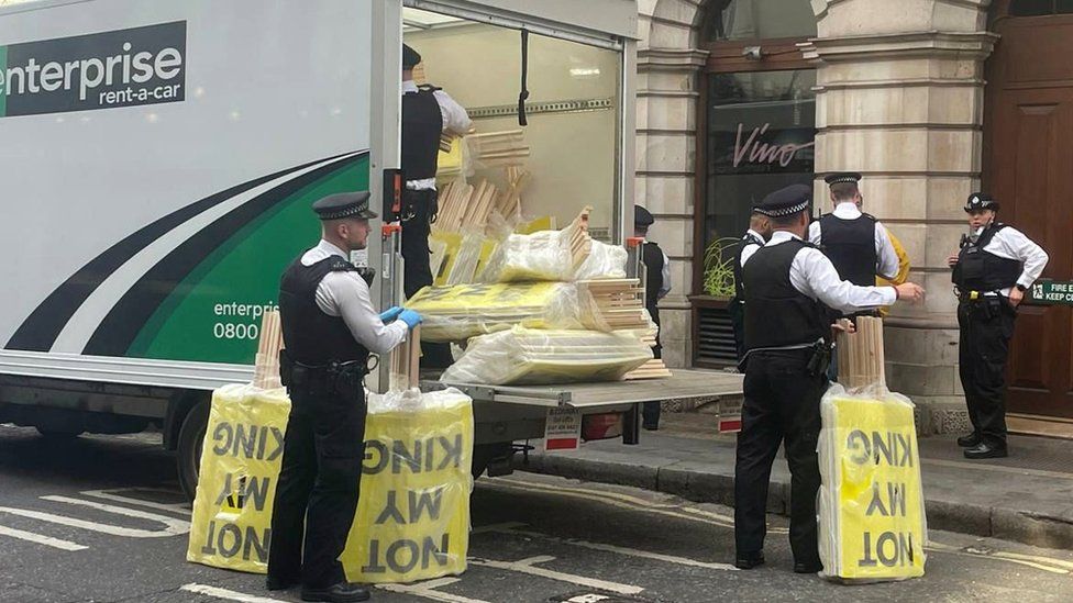 Officers seizing signs from a back of a lorry reading "Not my king"