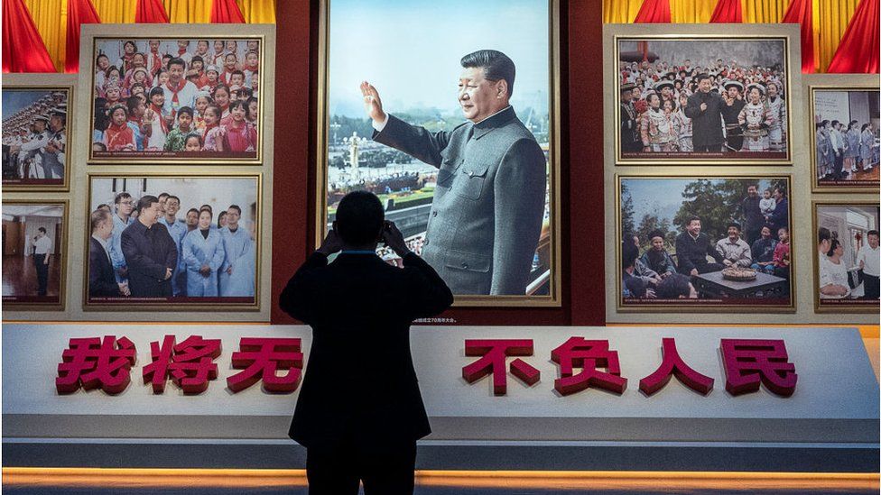 A visitor takes a photo of a display showing images of Chinese President Xi Jinping at the Museum of the Communist Party, on October 13, 2022 in Beijing, China