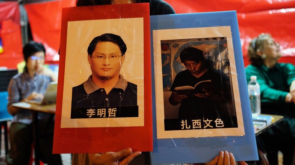 A volunteer holds placards of detained Taiwanese activist Lee Ming-cheh and Tibetan education advocate Tashi Wangchuk in Taipei on June 4, 2017
