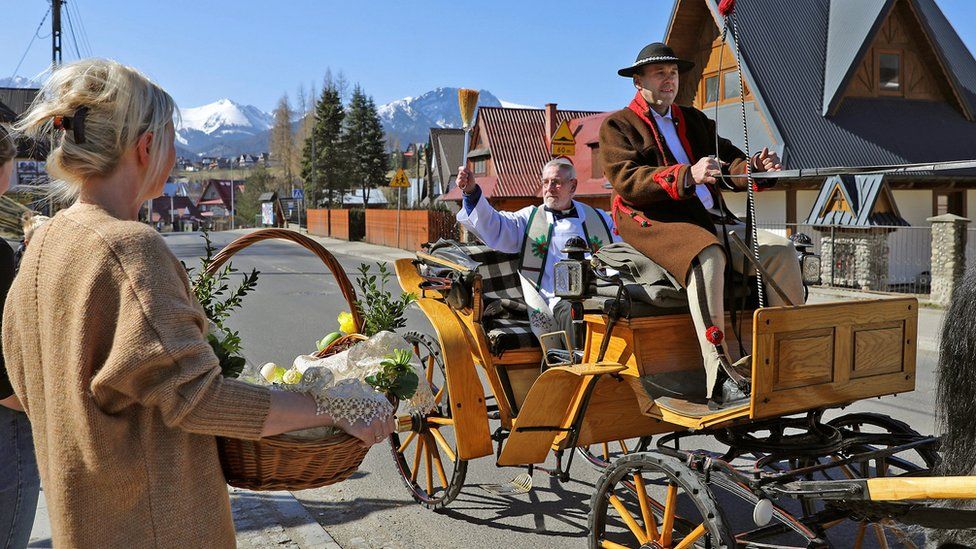 A priest sprinkles holy water on believers and their food while circuiting in a horse-drawn cart all over the vicinity during the celebrations of Holy Saturday in Zakopane, Poland