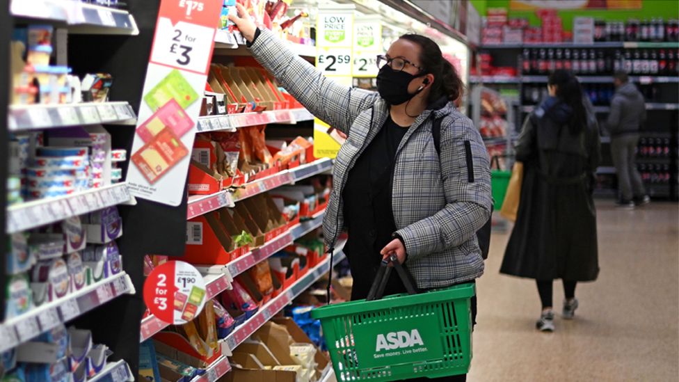 Покупатель в маске выбирает товары с полок супермаркета Asda