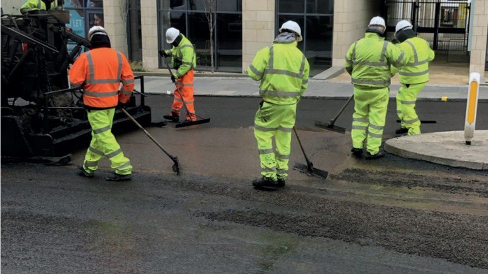 Workers applying road surface material