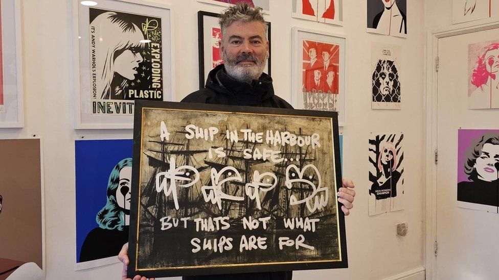Artist Pure Evil standing in front of his new exhibition
