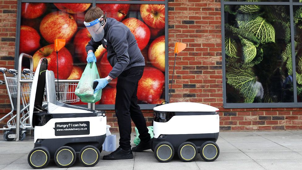 A Co-op supermarket worker loads a Starship delivery robot with groceries in Milton Keynes