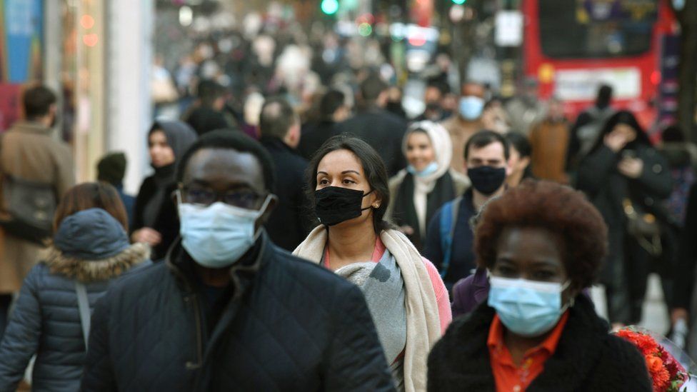 Shoppers walk along Oxford Street, many of whom are wearing masks