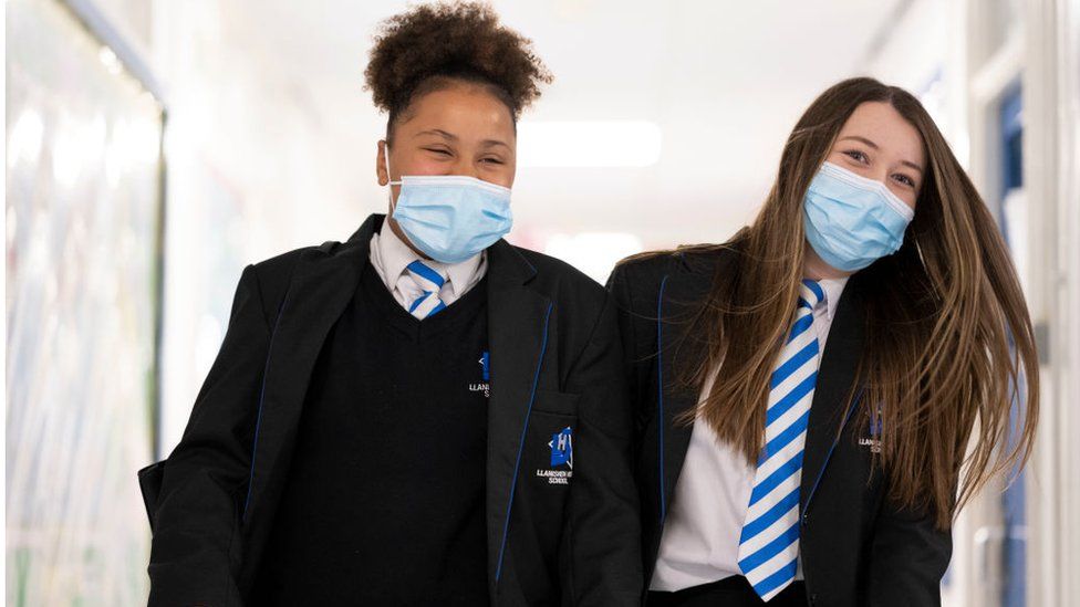 Two girls wearing face masks walk down the corridor of Llanishen High School