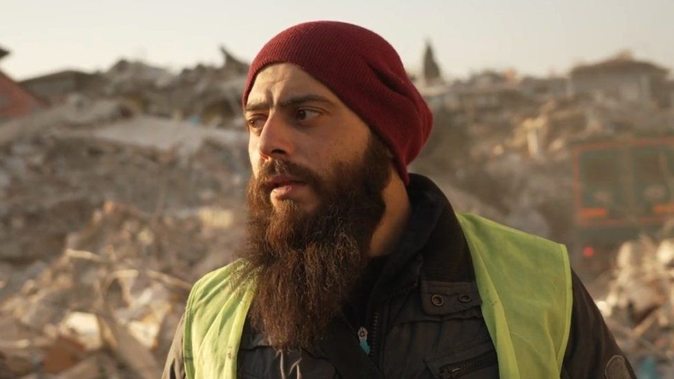 Ali, a Syrian, stands in front of collapsed buildings in Antakya, Turkey