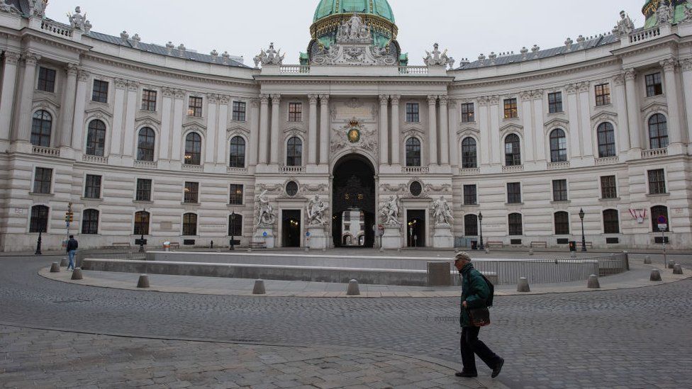 En mann krysser Michaelerplatz foran Hofburg-palasset på den første dagen av en landsomfattende, midlertidig sperring under den fjerde bølgen av den nye koronaviruspandemien 22. november