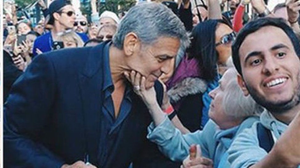 Elfriede Wolf reaches out and grabs George Clooney's face as he walks the red carpet