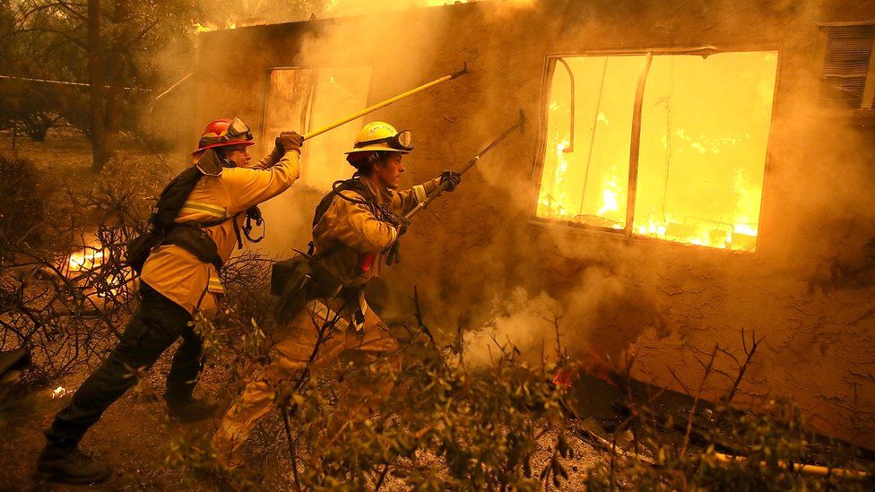 Firefighters try to keep flames from burning home from spreading to a neighbouring apartment complex as they battle the Camp Fire in November 2018