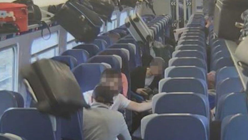 Luggage falling from overhead racks onto passengers on a train.