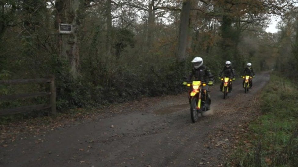 TV off-road motorbike team riding through forest