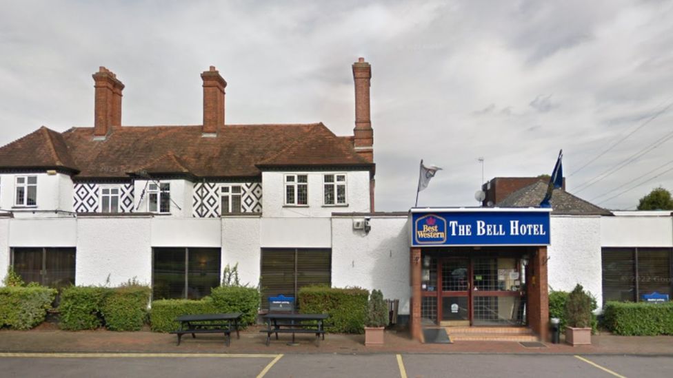 Image of the outside of the Bell Hotel in Epping Forest. The building is white with a blue sign on the door with yellow writing