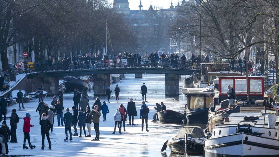People walk and skate on ice on the Prinsengracht canal in Amsterdam, The Netherlands, 13 February 2021.