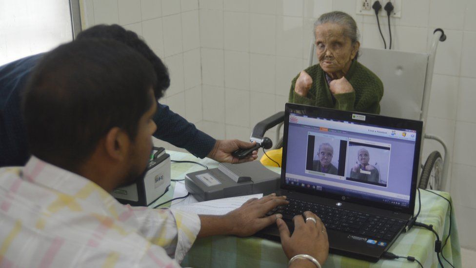 Officials take Sajida Begum's picture for her Aadhaar card