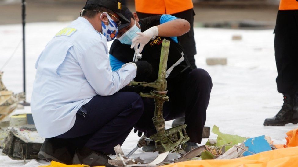 Indonesian officials inspect suspected debris from the plane