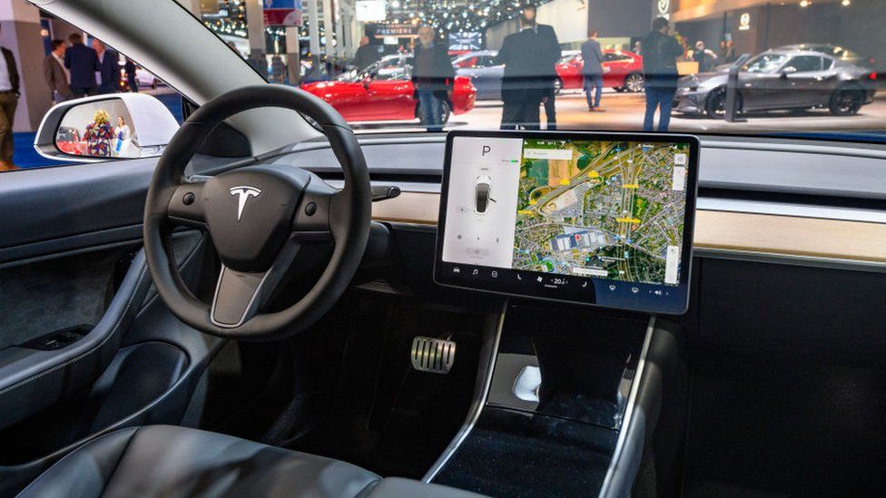 The interior of the Tesla Model 3, shown with a large tablet-like device mounted in the central console to the side of the steering wheel