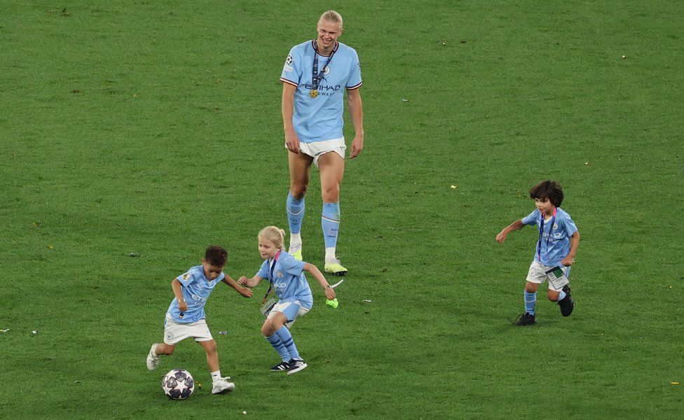 Manchester City's Erling Braut Haaland on the pitch with kids after winning the Champions League