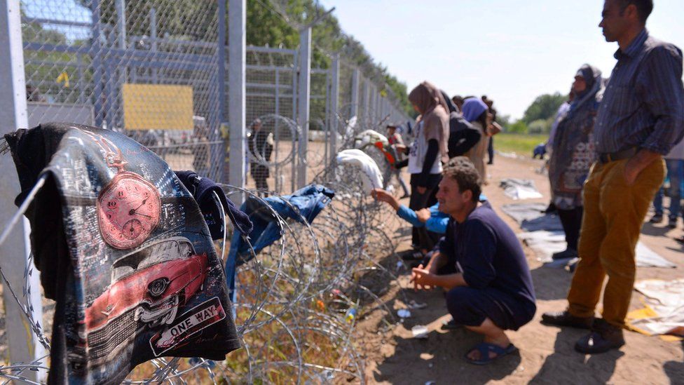 Migrants stand by the border fence in a makeshift camp near the Horgos border crossing into Hungary, near Horgos, Serbia, on 27 May
