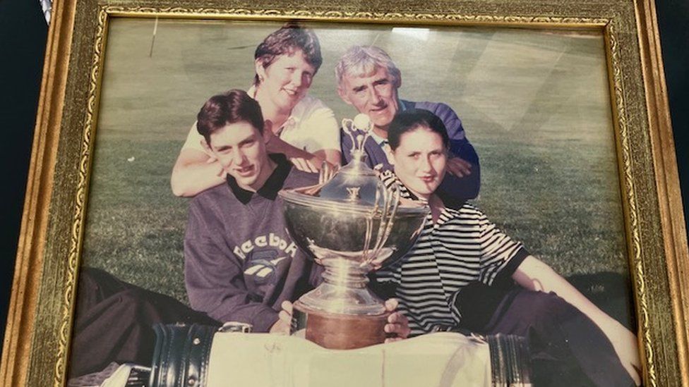 An old photo of James with his parents and sister with a golf trophy