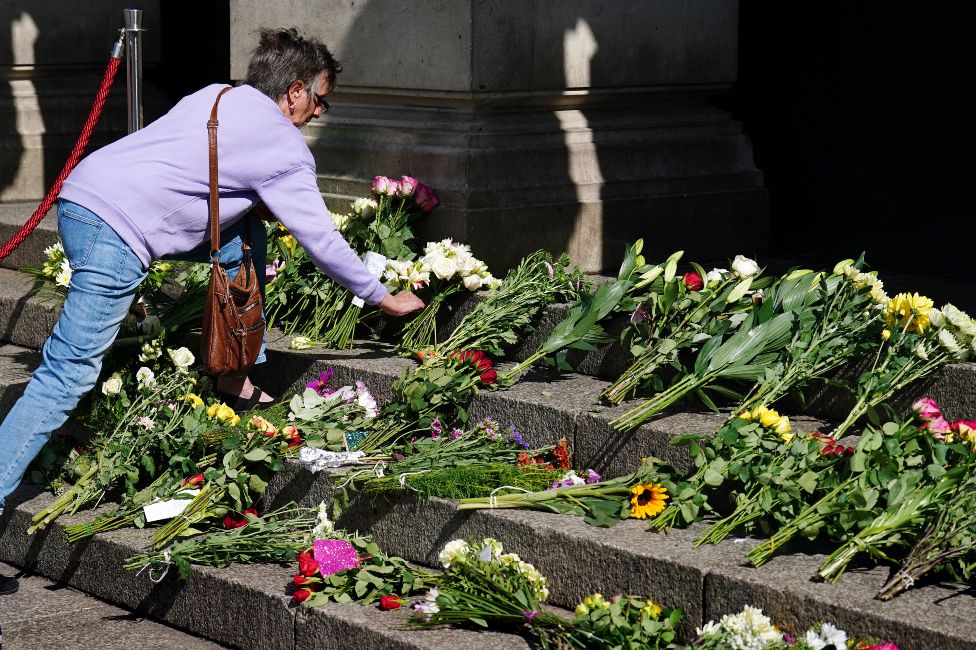 A woman lays flowers at Nottingham Council steps