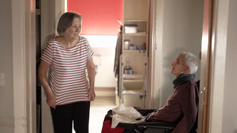 A woman talks to a man in a wheelchair