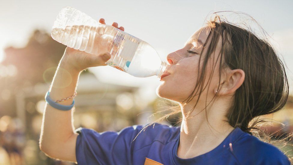girl drinking from plastic water bottle