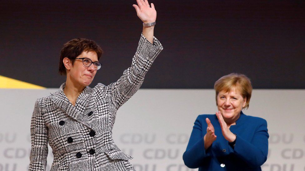 Annegret Kramp-Karrenbauer waves next to German Chancellor Angela Merkel after being elected as the party leader