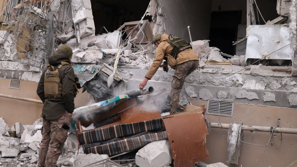 Ukrainian service men remove a grad rocket in a damaged house in Kherson