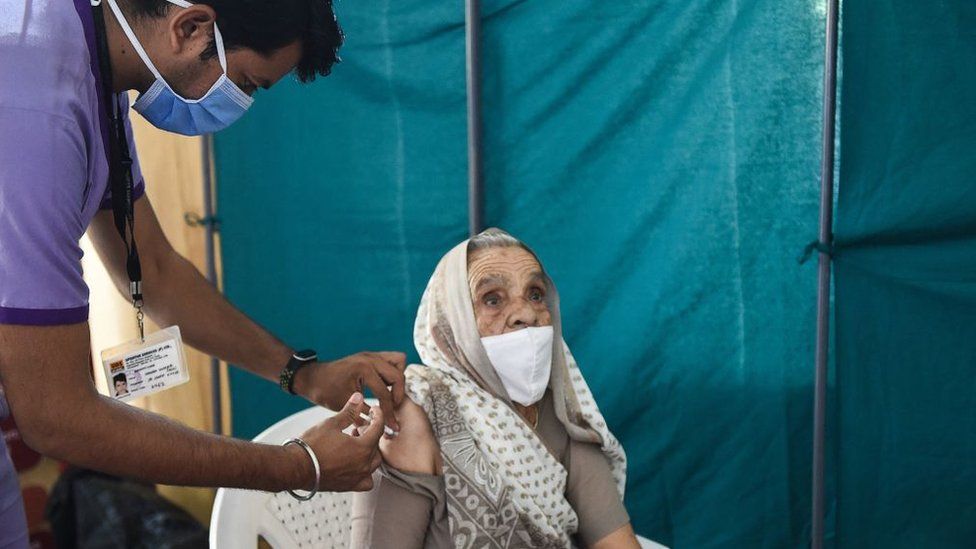 A health worker gives an elderly woman a Covid-19 vaccine at the Tagore Hall in Ahmedabad on 18 March 2021