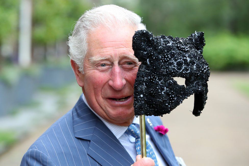 Prince Charles holds a face mask