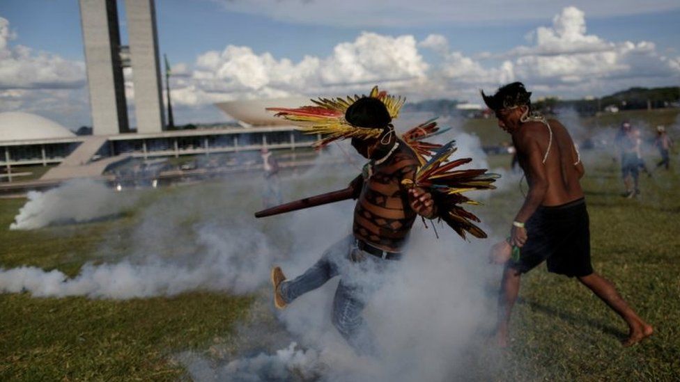 Indigenous protesters kick at canisters of tear gas at a demonstration in Brasilia on 25 April 2017