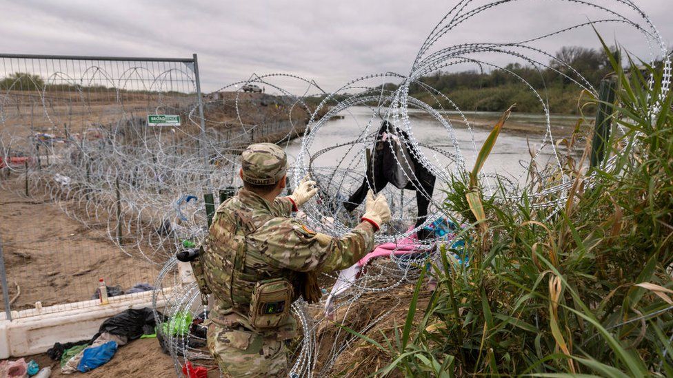 A Texas National Guard soldier installs additional razor wire at the border