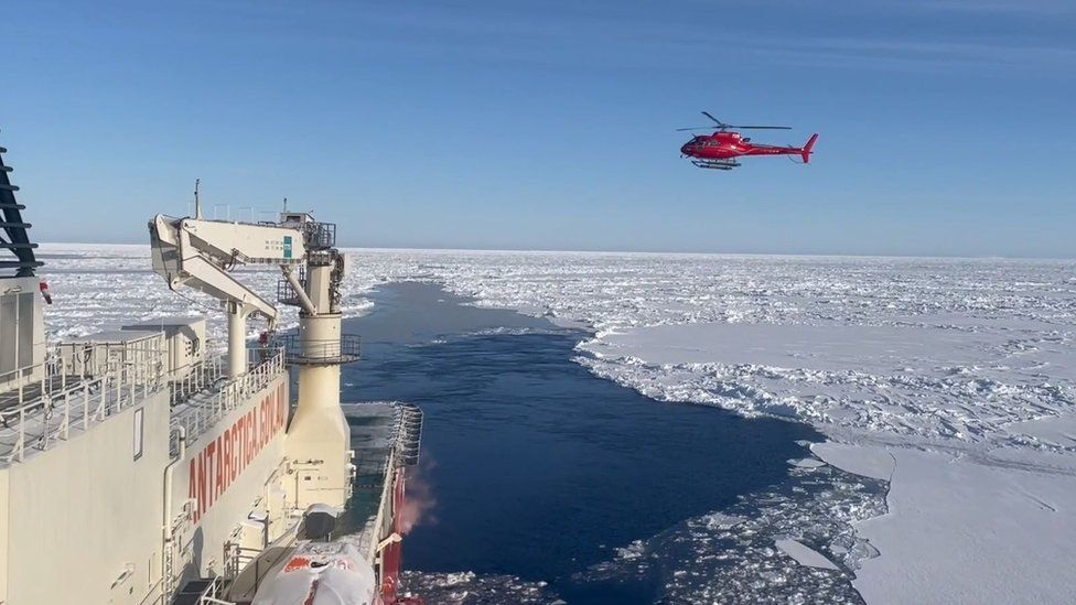 A chopper  returns to an icebreaker vessel  successful  Antarctica