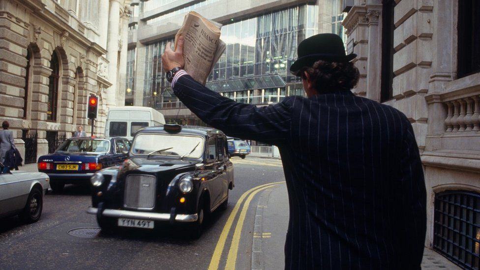 Man in bowler hat hailing a taxi