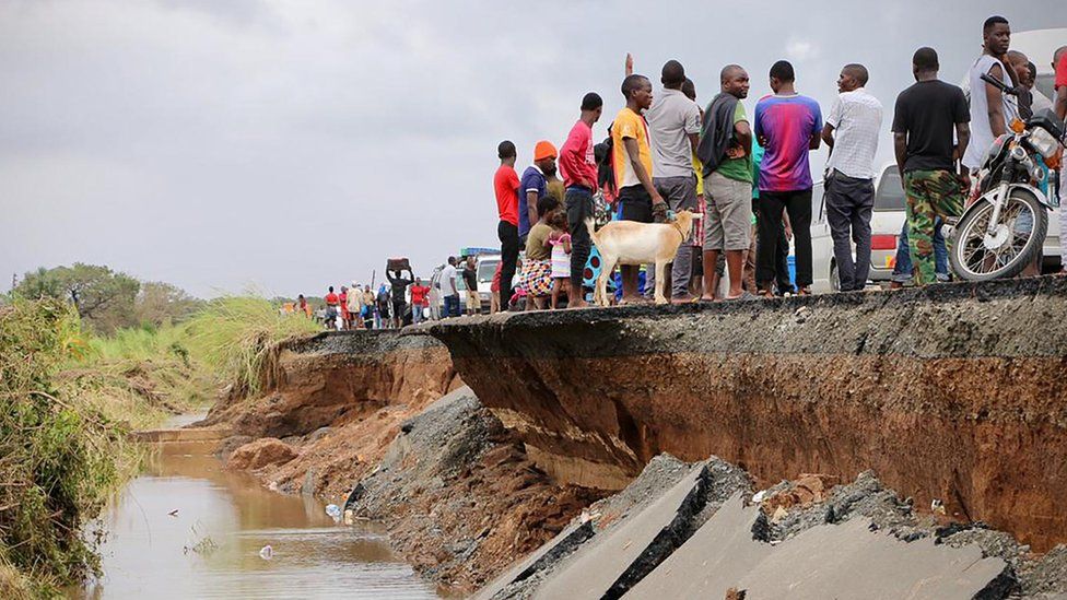 People gather on a destroyed section of road